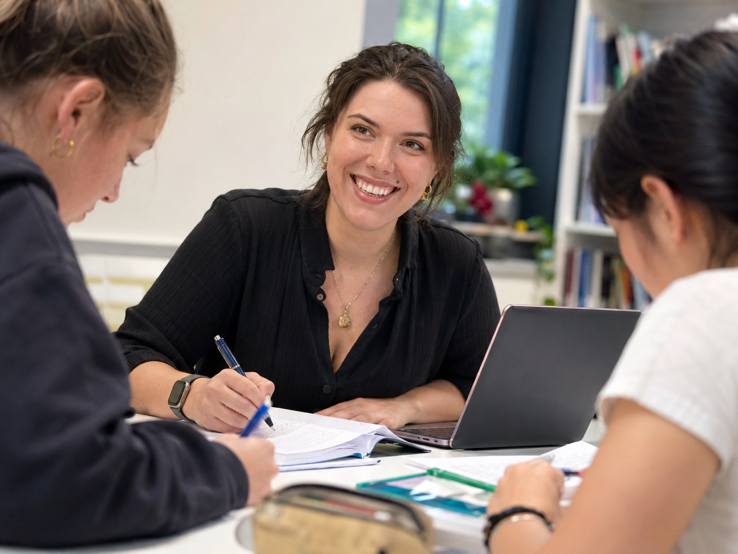 Ruth Prentice at a desk with a laptop, working through notes with two students